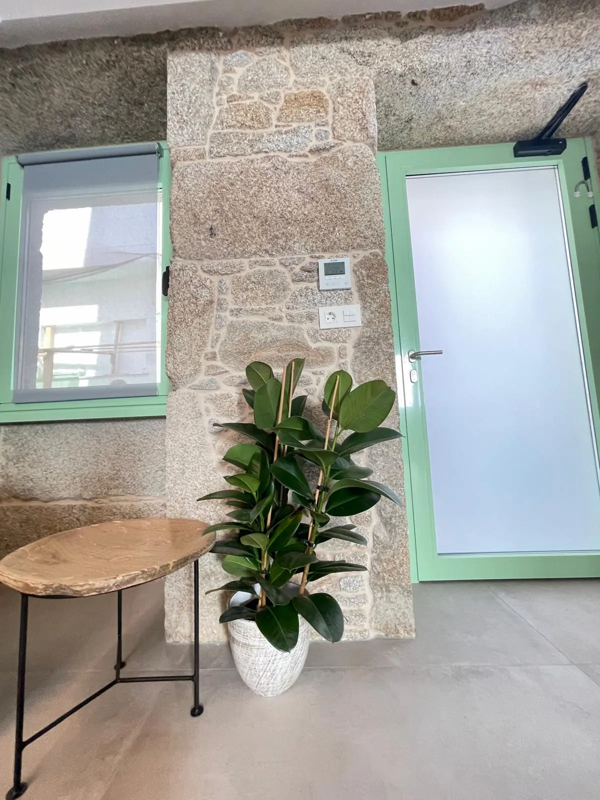Entrada interior de piedra con carpintería verde